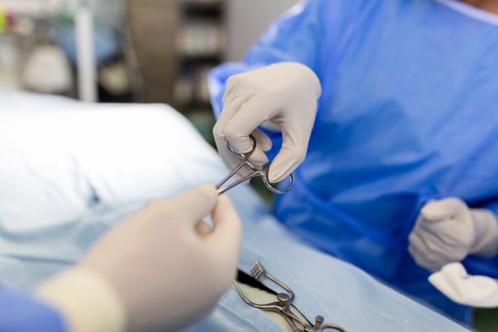 Shot in the Operating Room, Assistant Hands out Instruments to Surgeons During Operation. Surgeons Perform Operation. Professional Medical Doctors Performing Surgery.